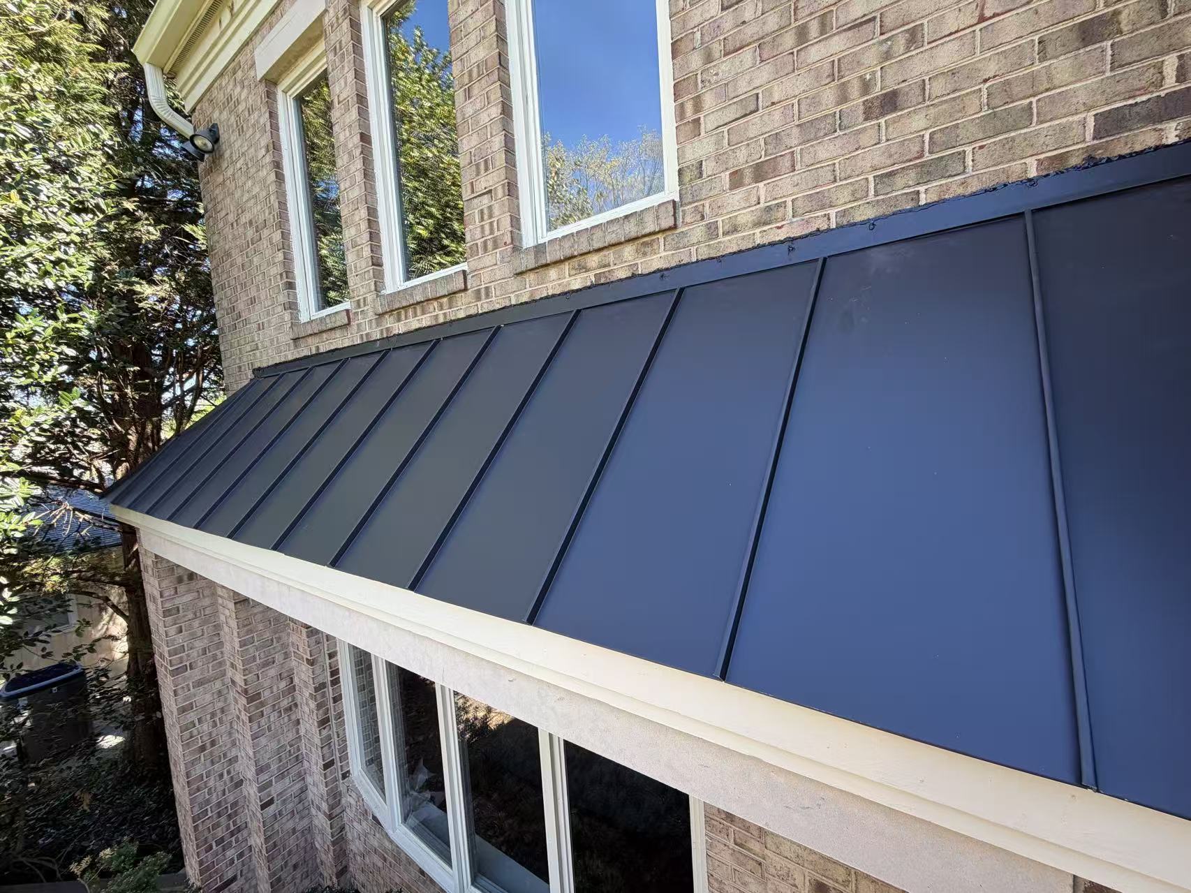 Dark metal roof installation on brick home